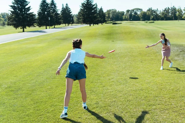 Hermosas chicas adolescentes jugando con disco volador en el parque - foto de stock