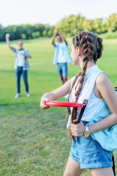 Bella ragazza adolescente lancio disco volante per gli amici nel parco — Foto stock