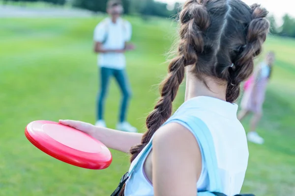 Вид сзади девочки-подростка, бросающей летящий диск в парке — стоковое фото