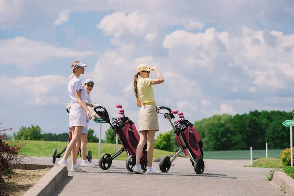 Golfisti di sesso femminile con attrezzature da golf a piedi al campo da golf — Foto stock