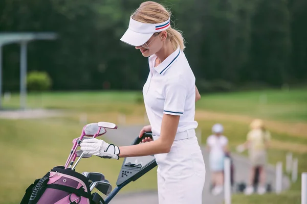 Foyer sélectif du joueur de golf féminin en casquette et polo blanc avec équipement de golf sur le terrain de golf — Photo de stock