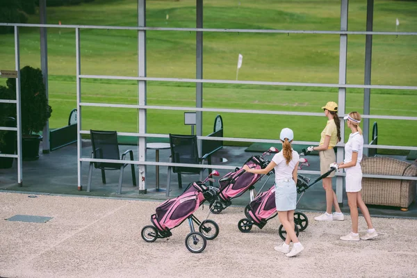 Side view of female golfers with golf gear walking at golf course on summer day — Stock Photo