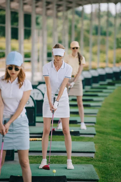 Selective focus of focused female golfers playing golf at golf course — Stock Photo