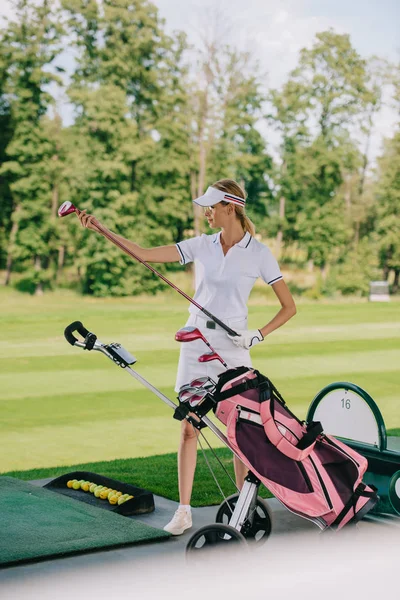 Jogador de golfe feminino em boné com equipamento de golfe no campo de golfe — Fotografia de Stock