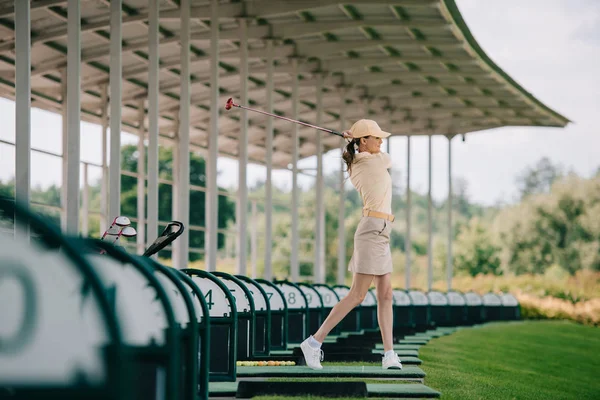 Mulher de boné amarelo e pólo jogando golfe no campo de golfe — Fotografia de Stock