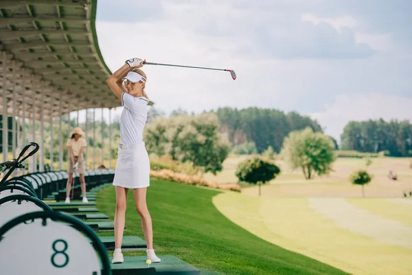 Foco seletivo de sorrir golfista feminina no pólo e boné jogar golfe no campo de golfe — Fotografia de Stock