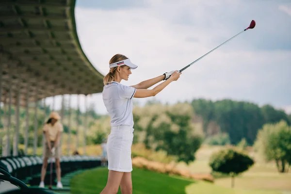 Selective focus of female golfer in polo and cap playing golf at golf course — Stock Photo