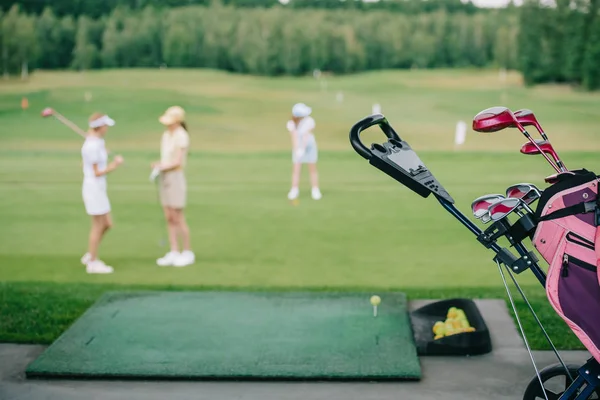 Selektiver Fokus von Golfausrüstung und Frauen in Mützen auf dem Golfplatz — Stockfoto