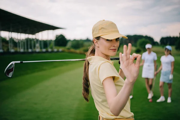 Selective focus of female golf player with golf club showing ok sign at golf course — Stock Photo