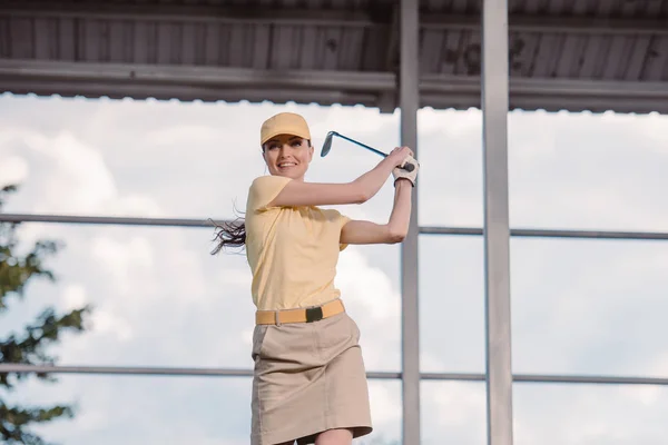 Портрет улыбающейся гольфистки в кепке с клюшкой для гольфа в руках — стоковое фото