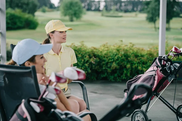 Seitenansicht von Frauen in Mützen, die nach einem Golfspiel auf dem Golfplatz ruhen — Stockfoto