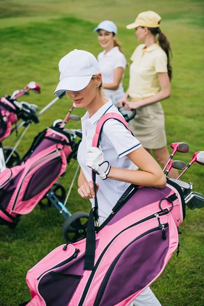Selective focus of women in caps with golf equipment on golf course — Stock Photo