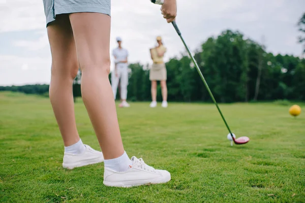 Schnappschuss von Frau beim Golfspielen, während Freunde in der Nähe auf Golfplatz stehen — Stock Photo