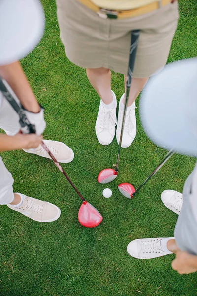 Vue aérienne des joueuses de golf avec des clubs de golf debout sur la pelouse verte avec balle de golf au milieu — Photo de stock