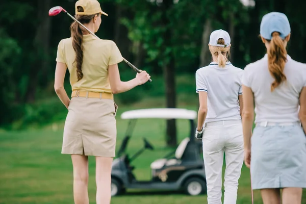 Vue arrière des femmes avec équipement de golf marchant sur la pelouse verte au terrain de golf — Photo de stock