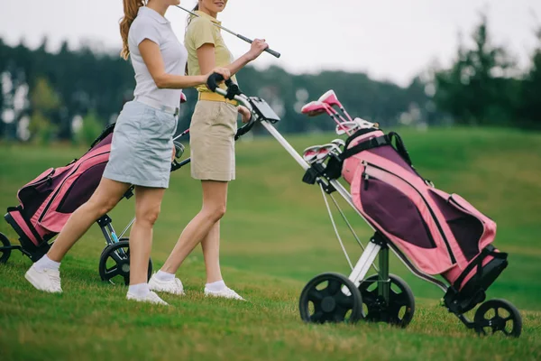 Vista parcial de las jugadoras de golf en polos caminando en el campo de golf - foto de stock