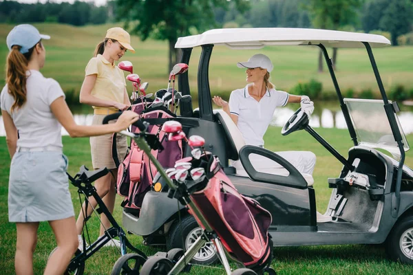 Joueuses de golf en casquettes au chariot de golf sur le terrain de golf — Photo de stock