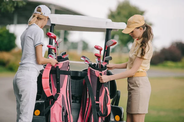 Women in polos and caps with golf equipment at golf course on summer day — Stock Photo