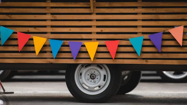 Wheels and bottom part of food truck with colorful flags — Stock Photo