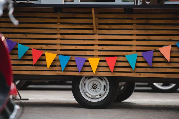 Wheels and bottom part of food truck with colorful flags — Stock Photo