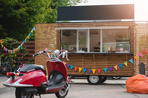 Scooter vermelho e caminhão de alimentos com bandeiras coloridas atrás — Fotografia de Stock