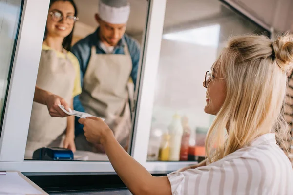 Lächelnde junge Frau zahlt in Foodtruck — Stockfoto