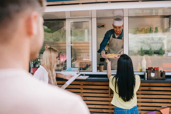 Enfoque selectivo de los jóvenes que compran comida rápida en camión de comida - foto de stock