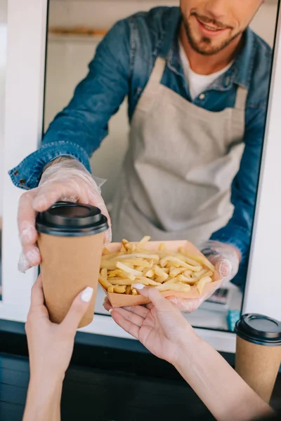 Plan recadré de chef donnant des frites et du café pour aller au client dans un camion alimentaire — Photo de stock