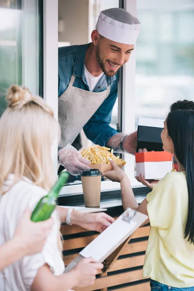 Happy chef giving french fries to customer from food truck — Stock Photo