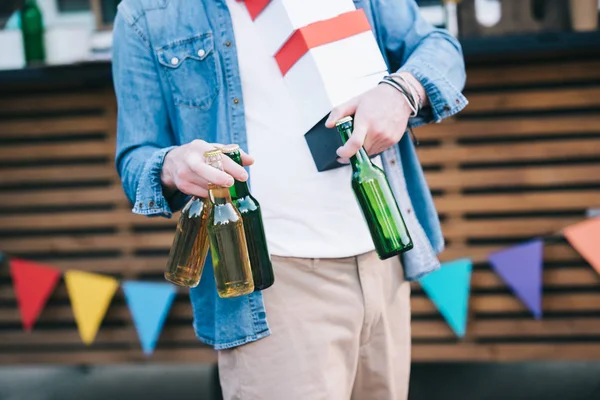 Обрезанное изображение человека, держащего бутылки пива возле фургона с едой — стоковое фото