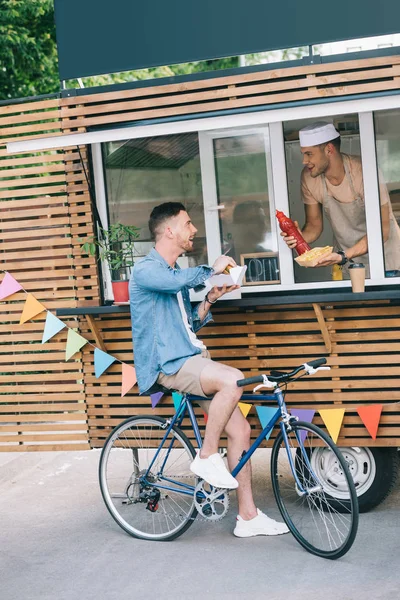 Chef giving hot dog and ketchup to customer from food truck — Stock Photo