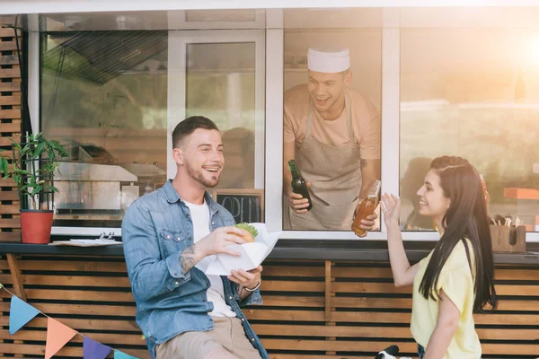 Chef sonriente dando orden a los clientes de camión de comida - foto de stock