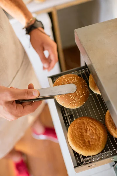 Image recadrée du chef frire du pain pour hamburgers dans un camion alimentaire — Photo de stock