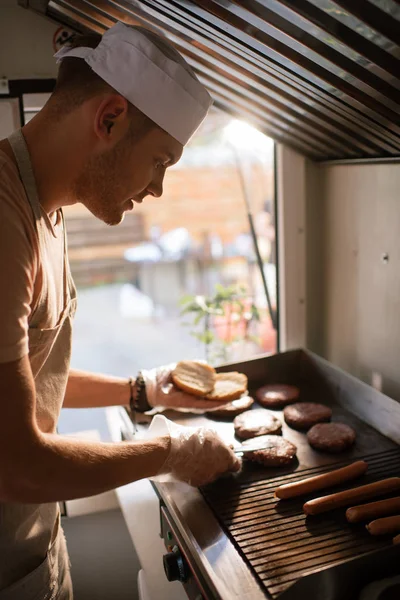 Side view of chef preparing burgers in food truck — Stock Photo