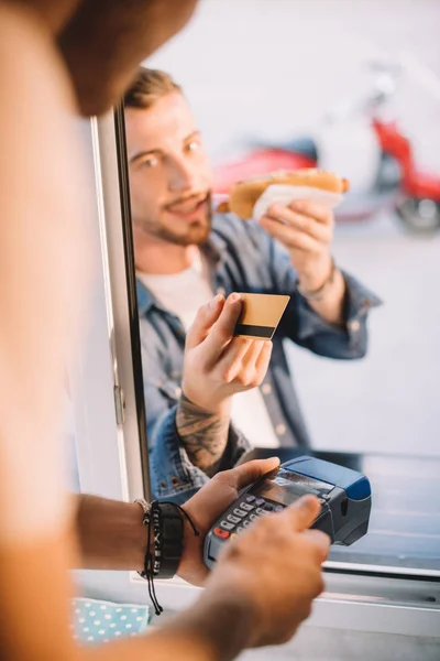 Imagem cortada do cliente dando cartão de crédito ao chef no caminhão de alimentos — Fotografia de Stock