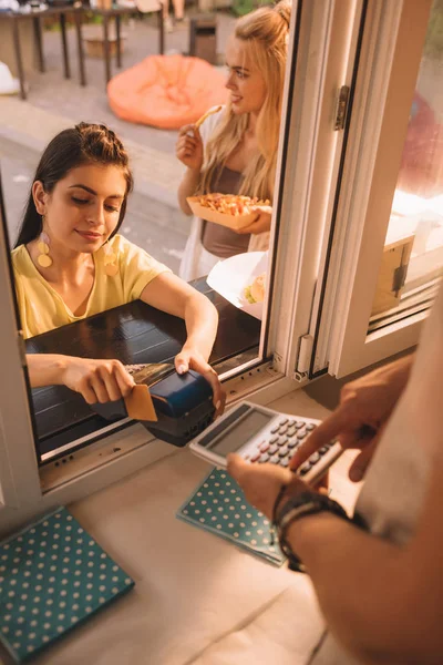 Vista de ángulo alto del cliente que paga con tarjeta de crédito en camión de comida - foto de stock