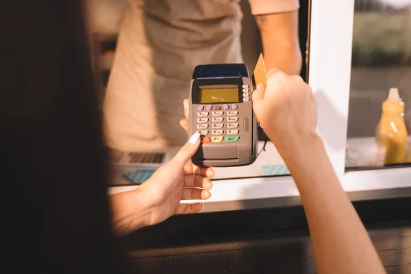 Imagen recortada del cliente que paga con tarjeta de crédito en camión de comida - foto de stock