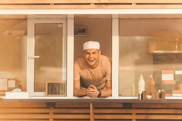 Lächelnd schaut der gut aussehende Koch von einem Food-Truck in die Kamera — Stockfoto
