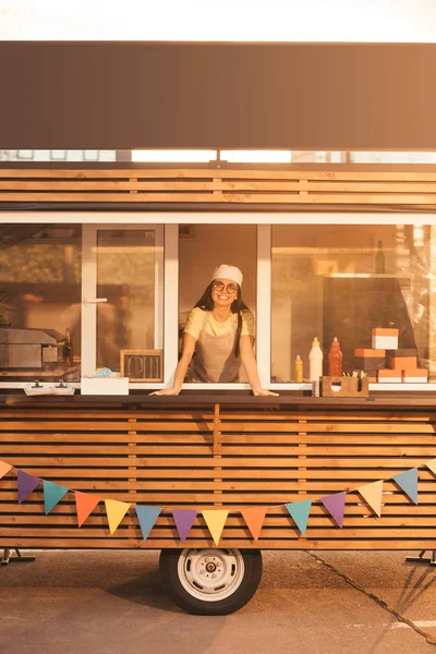 Happy beautiful chef looking at camera from food truck — Stock Photo