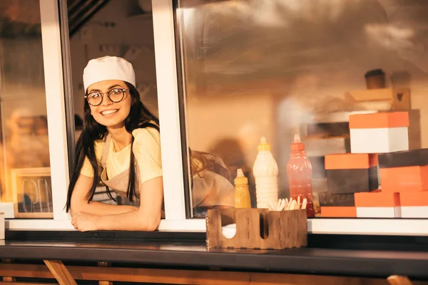 Sorridente bella chef guardando la fotocamera dal camion cibo — Foto stock
