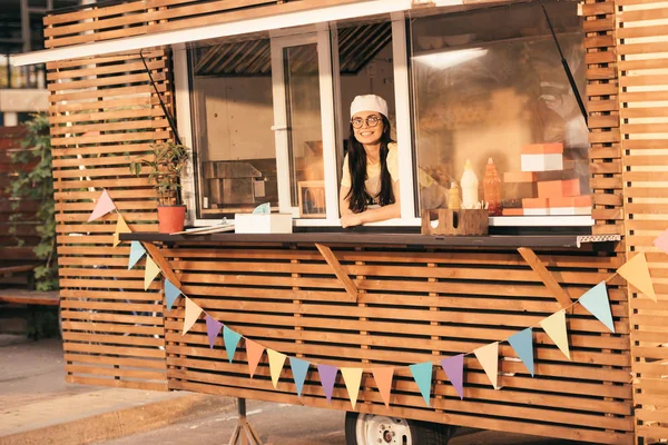 Smiling attractive chef looking at camera from food truck — Stock Photo