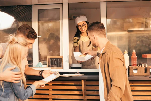 Customer taking burger from chef in food truck — Stock Photo