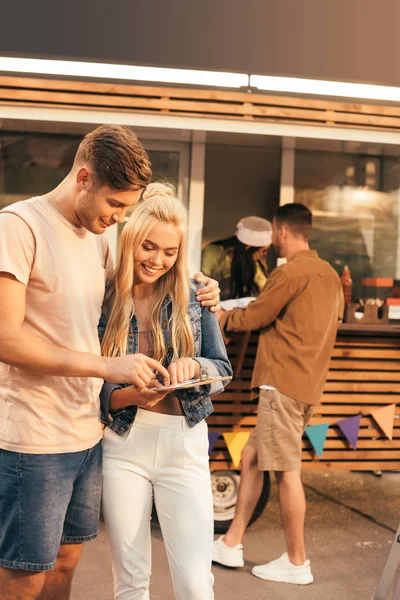 Smiling couple reading menu near food truck — Stock Photo