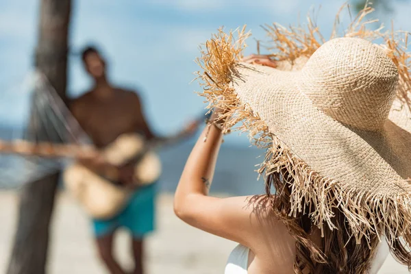 Messa a fuoco selettiva di ragazza in cappello di paglia e l'uomo a suonare la chitarra acustica — Foto stock