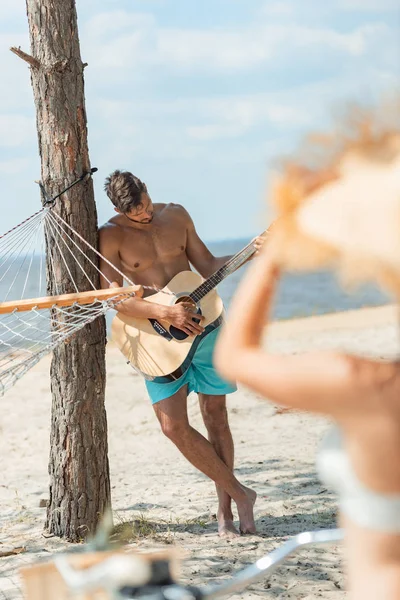 Selective focus of man playing acoustic guitar with girlfriend on foreground — Stock Photo