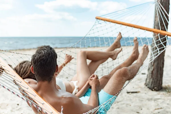 Casal de turistas relaxando na rede na praia perto do mar — Fotografia de Stock
