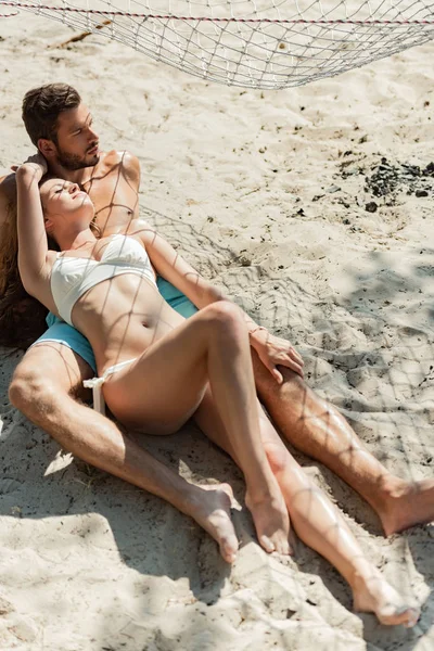 Feliz lindo casal deitado na praia de areia — Fotografia de Stock