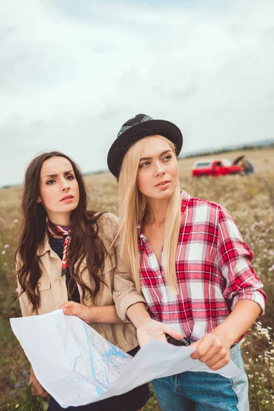 Novias jóvenes con mapa de pie en el campo y tratando de navegar - foto de stock