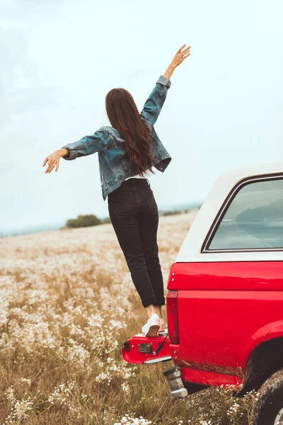 Вид ззаду жінки, що стоїть у багажнику автомобіля на квітковому полі — стокове фото