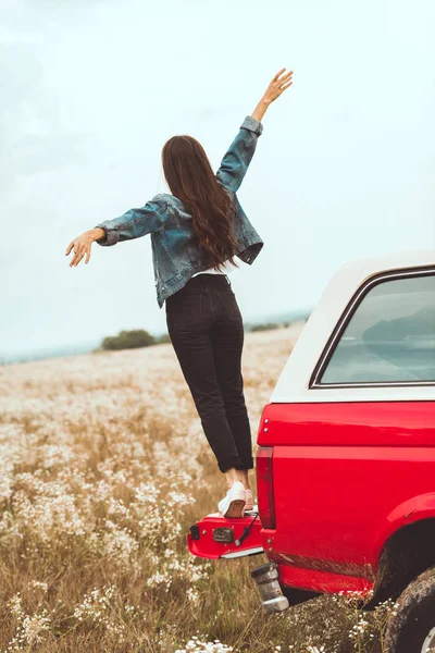 Rear view of woman standing in car trunk in flower field — Stock Photo